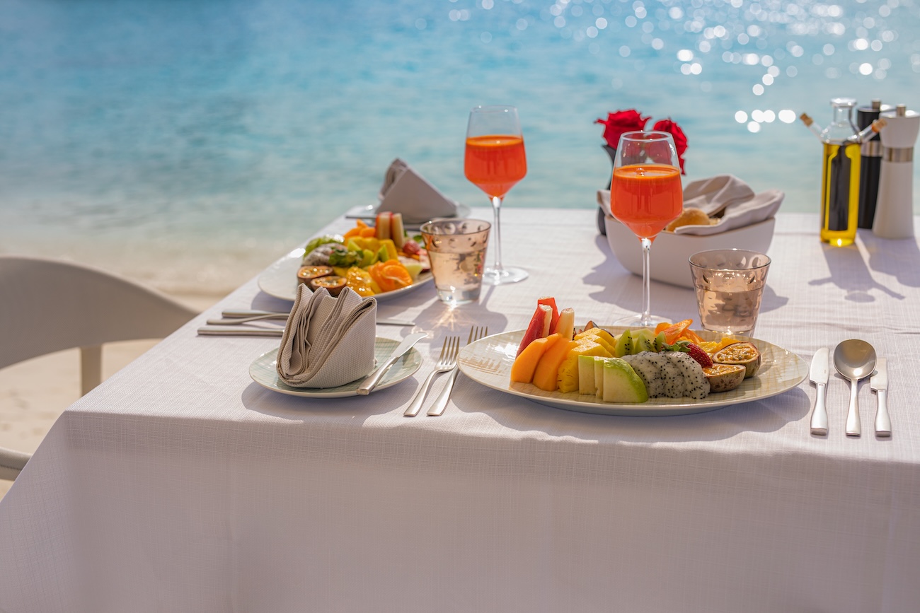 Luxury breakfast table with food for two with beautiful tropical sea view background. Morning couple time summer holiday and romantic vacation concept, luxury travel and lifestyle, destination dining