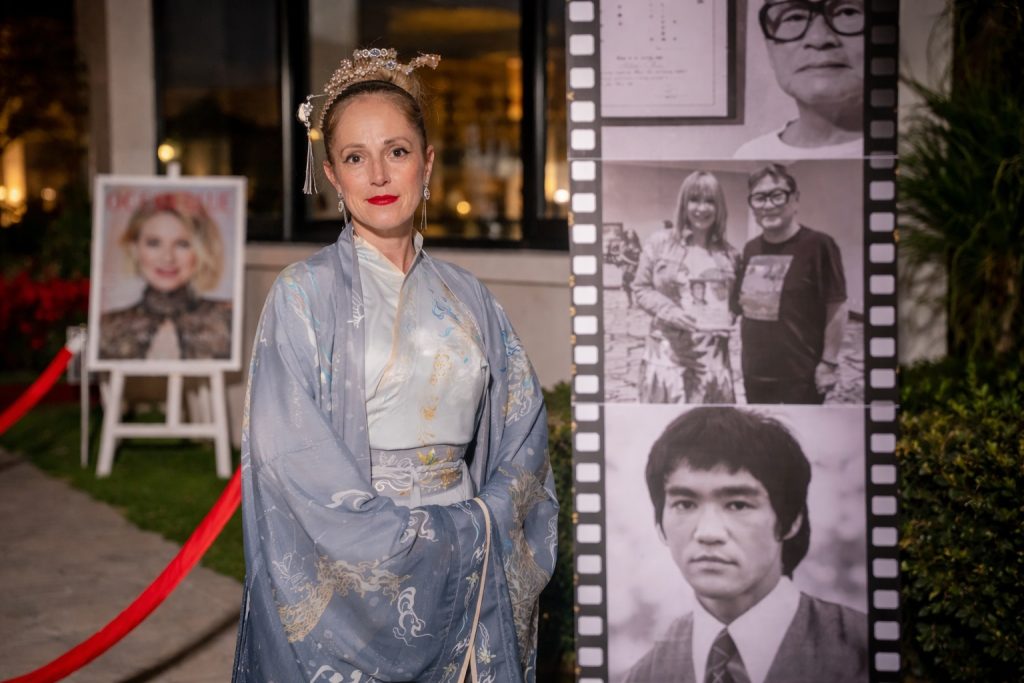 A traditional kimono-clad hostess stands beside memorable film stills of Chin and Lee